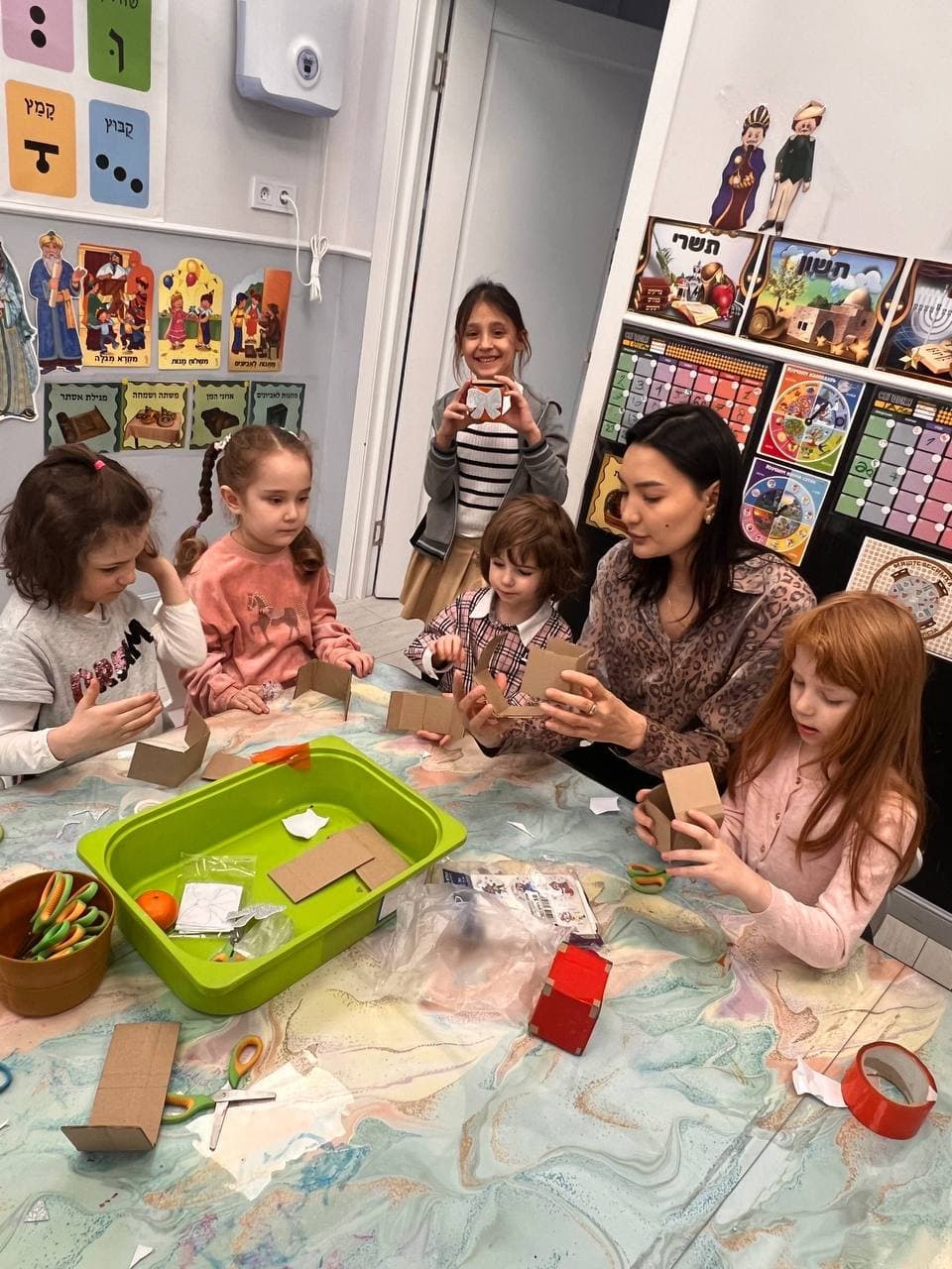 Дети с педагогом занимаются поделками за столом