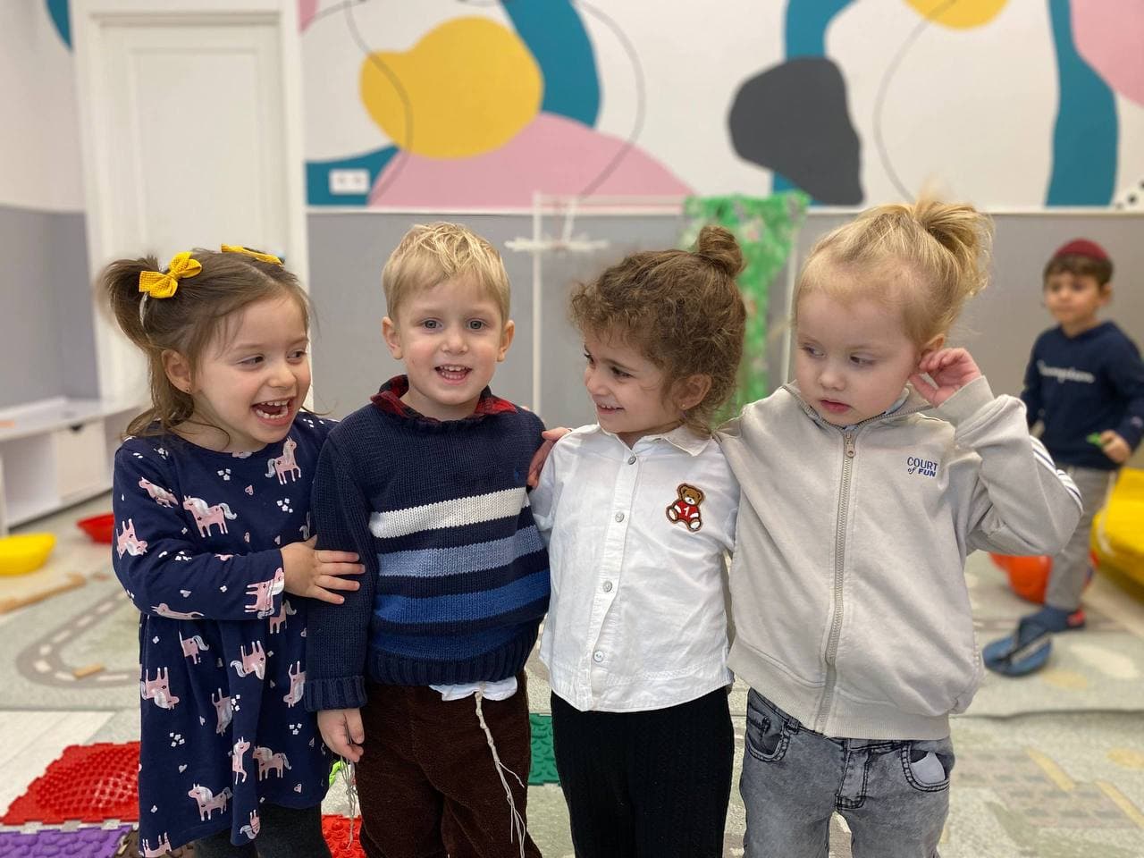 Группа детей улыбается в игровой комнате