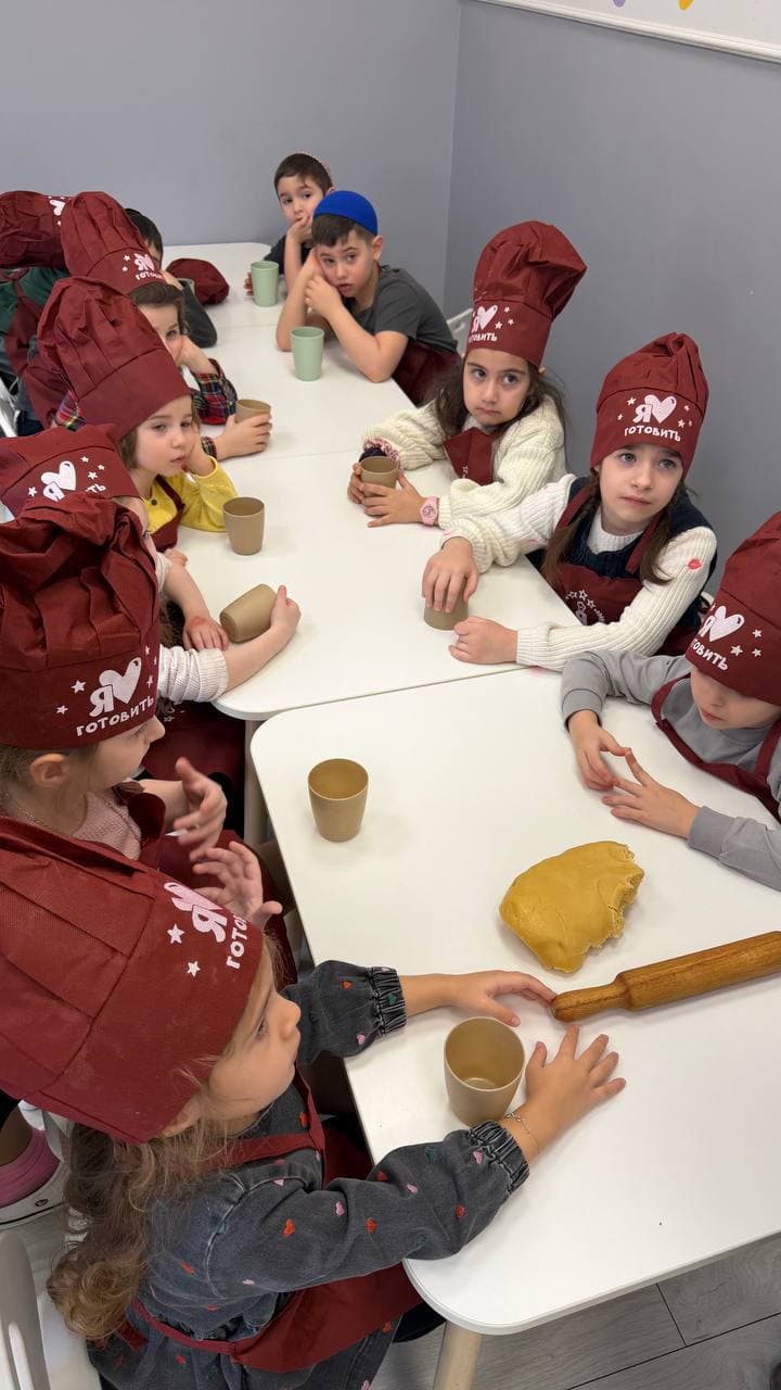 Группа детей в фартуках во время кулинарного урока